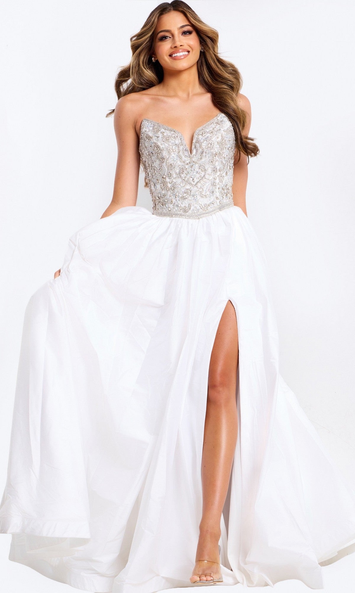 A woman models the Jovani 49247 Long Prom Dress: a strapless ball gown with an embellished bodice and a white satin A-line skirt with a high slit, set against a plain white background.
